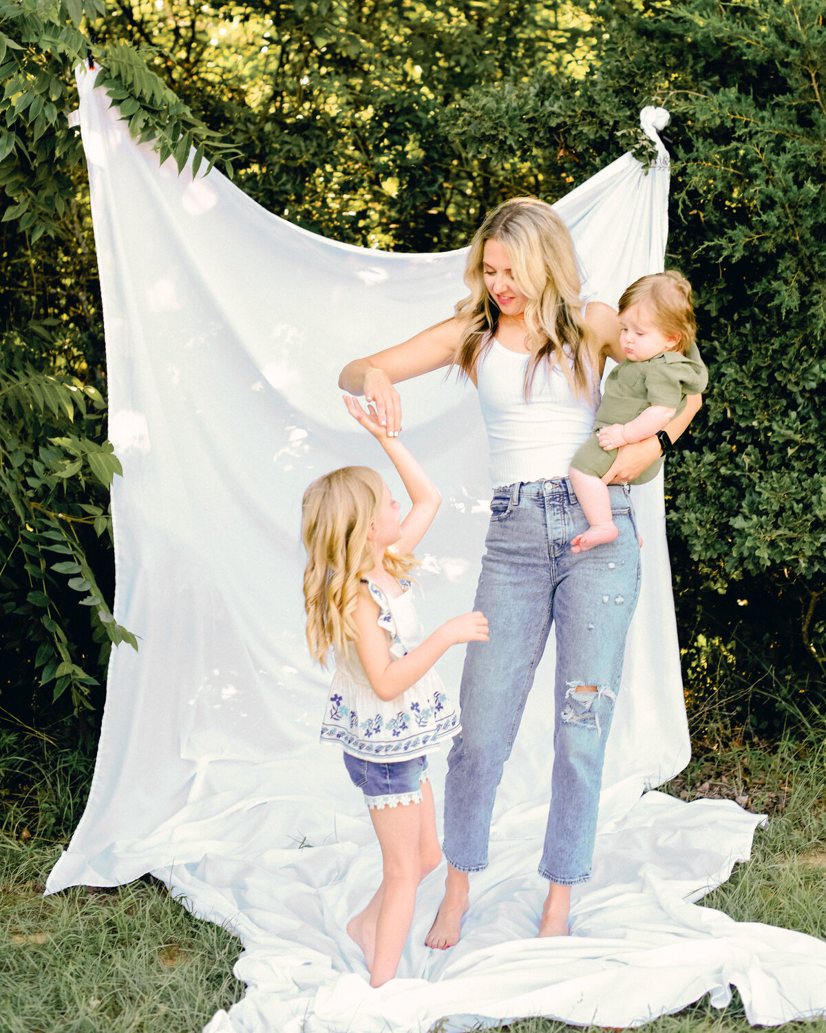Mother and children at an outdoor photography session with a white sheet.