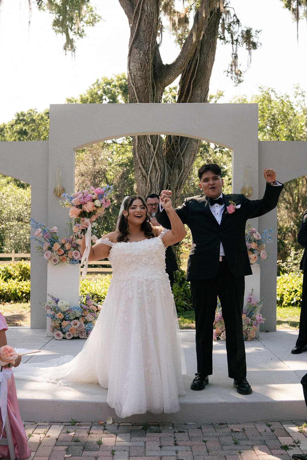 Bride and groom walking hand in hand in front of the floral ceremony arch at Uliana Estate in Lakeland.