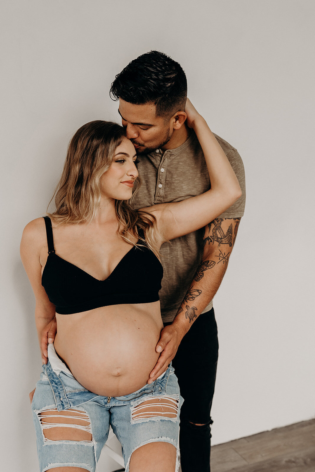 Editorial style image of husband kissing pregnant wife