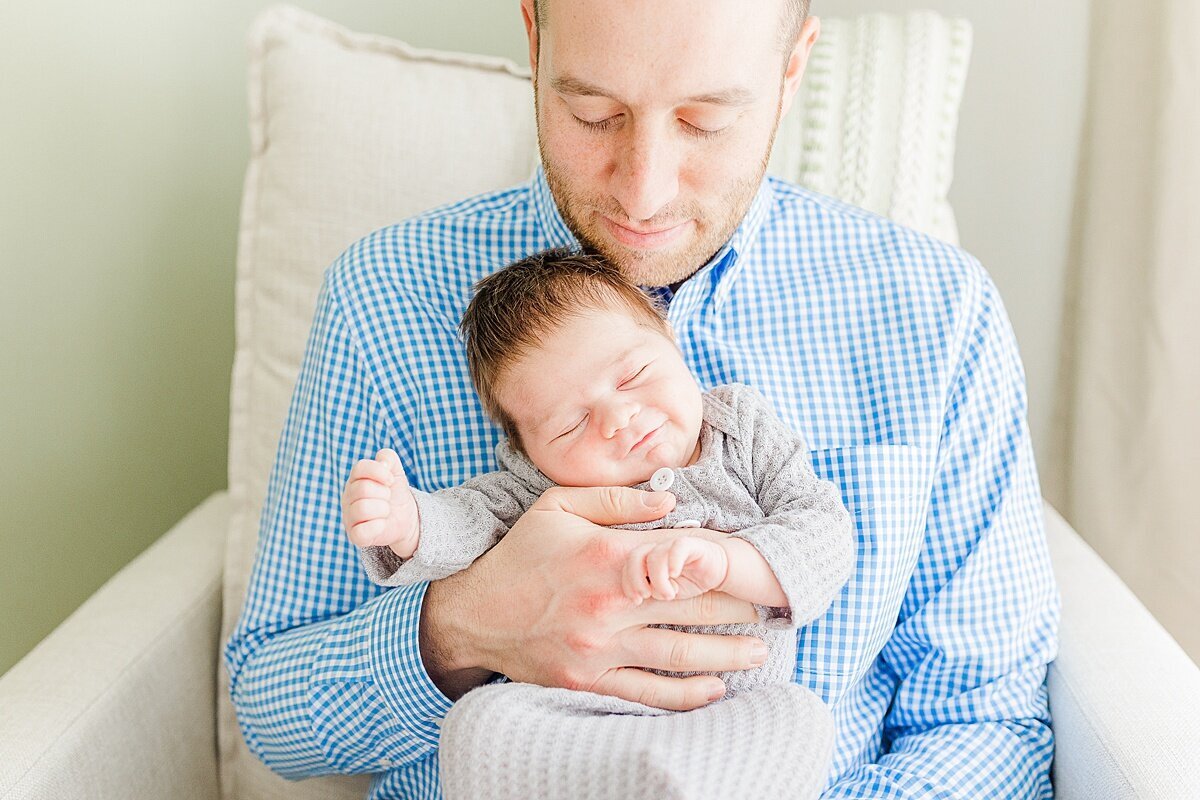 Dad holds smiling baby during in home newborn photo session with Sara Sniderman Photography  in Natick Massachusetts
