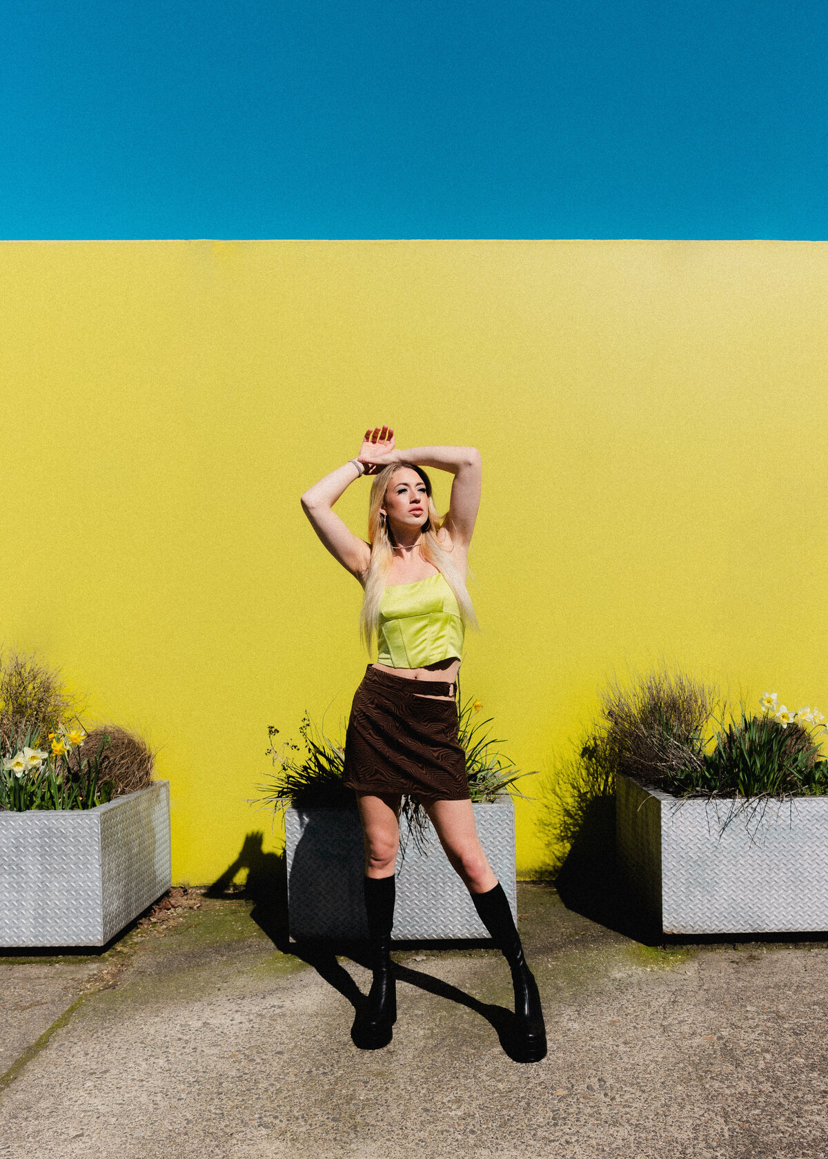 Woman striking a pose against a vibrant yellow and blue background – high-energy personal brand shoot by Mewphotovideo
