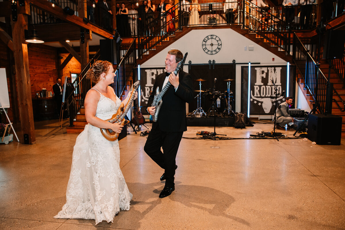 A father and daughter dance together with blow up guitars