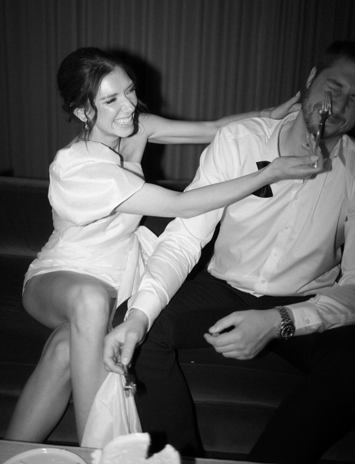 Bride playfully feeds groom cake in her short second wedding dress, Shinola Hotel, Michigan wedding venue