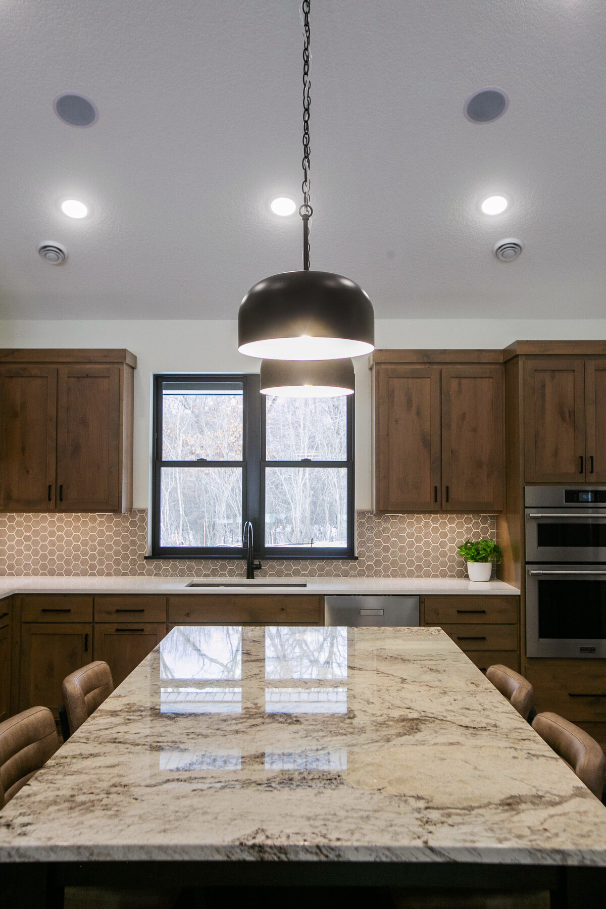 Open kitchen with dark cabinets, large island, and quartz countertops in an Elk River custom home