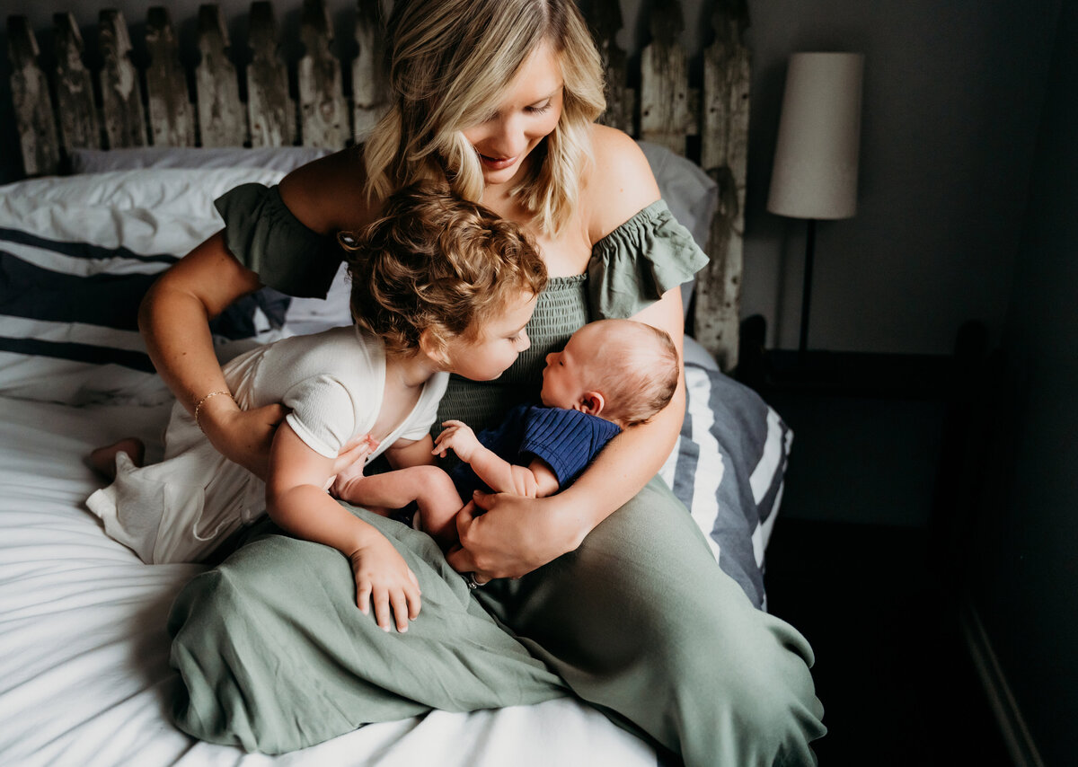 Newborn Photographer, a mother admires her two children as they sit in her lap