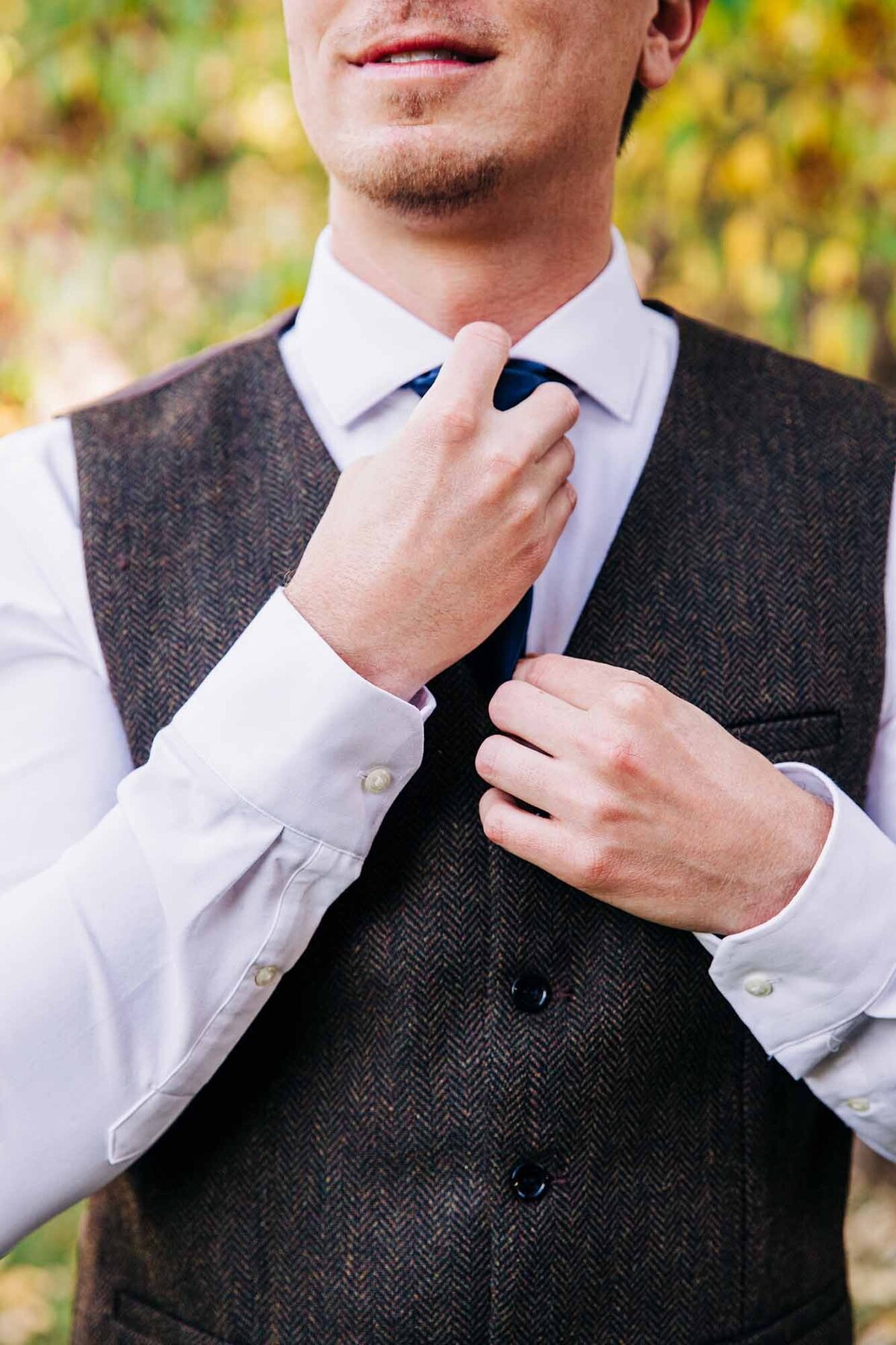 Groom adjusting tie before wedding ceremony