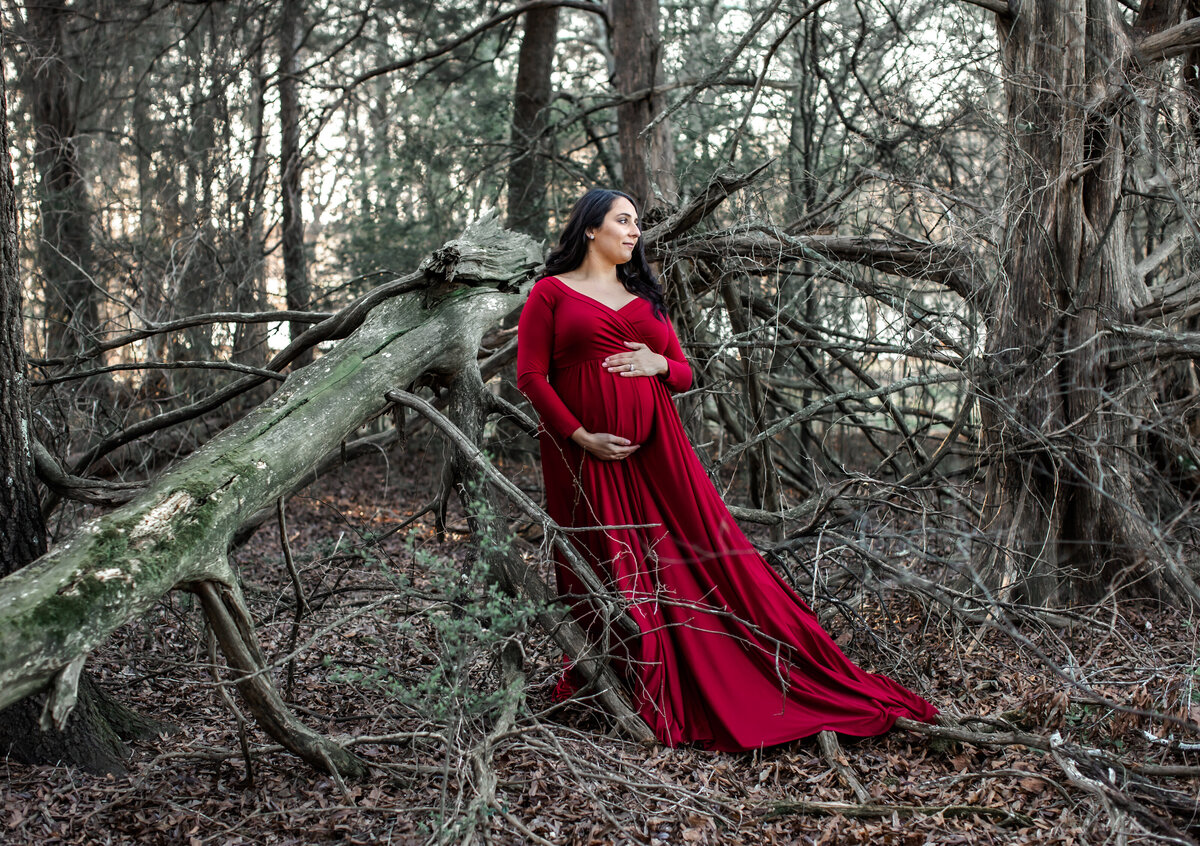 PREGNANT LADY IN RED DOWN POSING IN THE WOODS