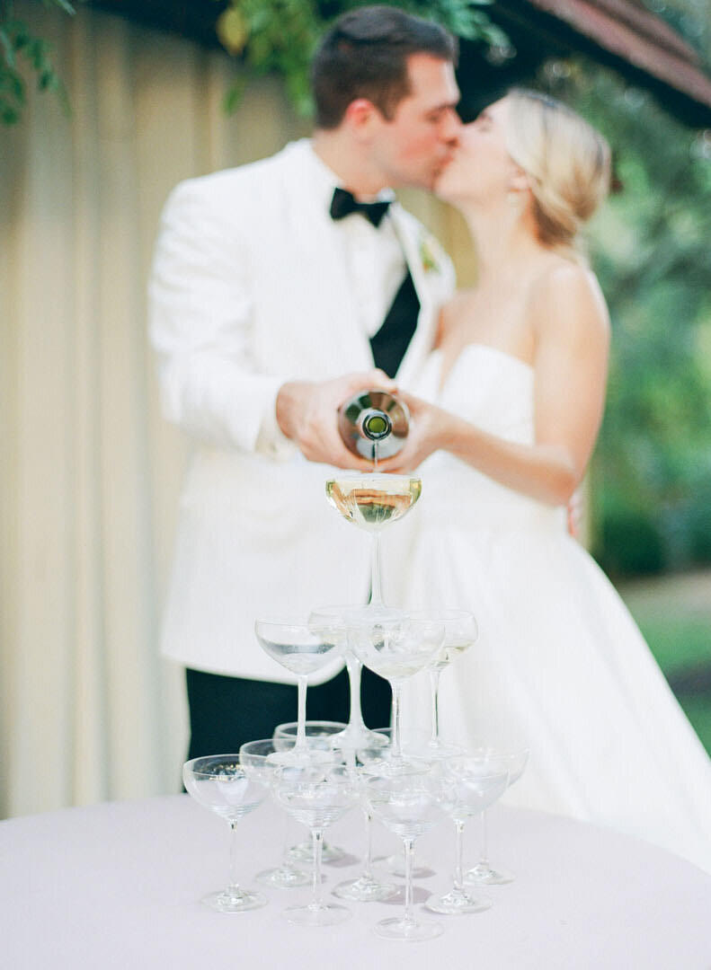 Bride and Groom Pouring Champagne into Tower Of Champagne Glasses Photo