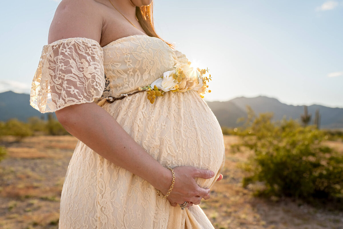 Maternity photo of baby bump with floral belt around it. Taken by Cactus & Pine Photography