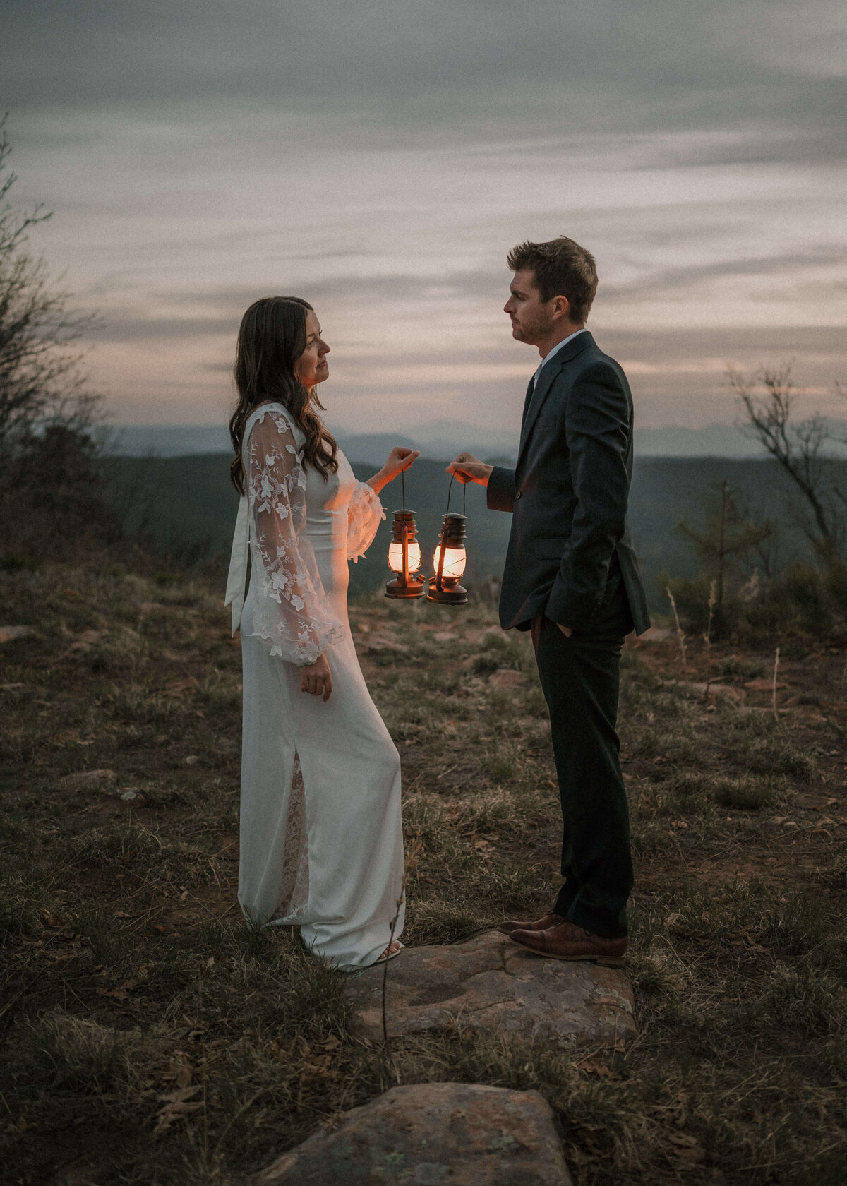 bride and groom holding lanterns and facing each other during mogollon rim elopement in payson, arizona