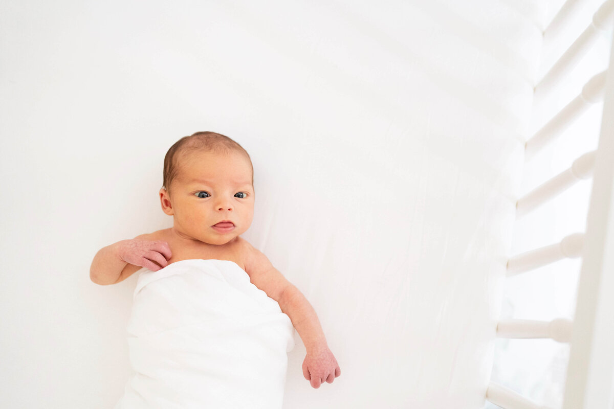 Newborn girl on white sheet in crib