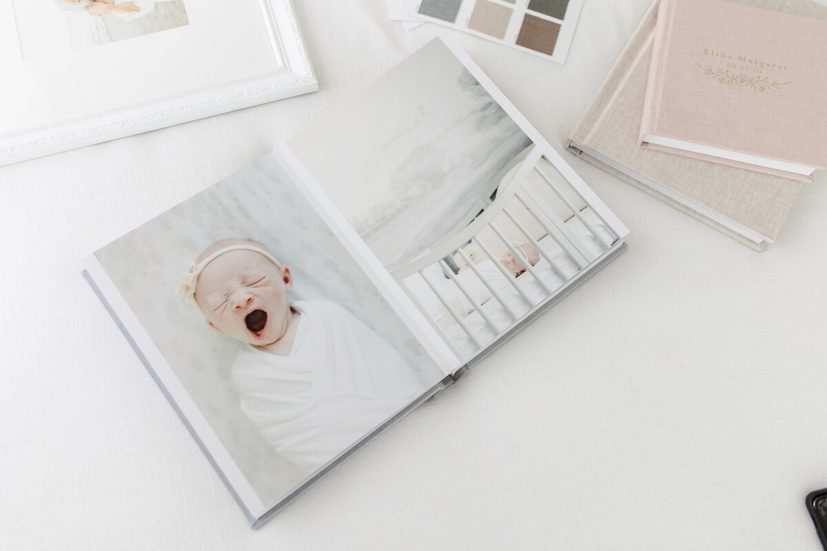 Heirloom family portrait album open to spread of yawning newborn baby