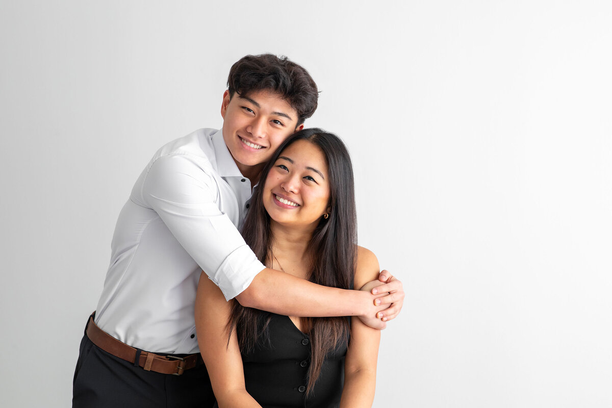 Two teens smile and pose together during their family photo session, showcasing a joyful and close-knit sibling bond