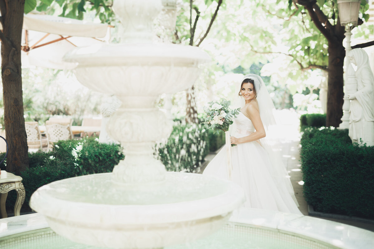 A bride outside with her bouquet at her summer wedding. Light and airy.