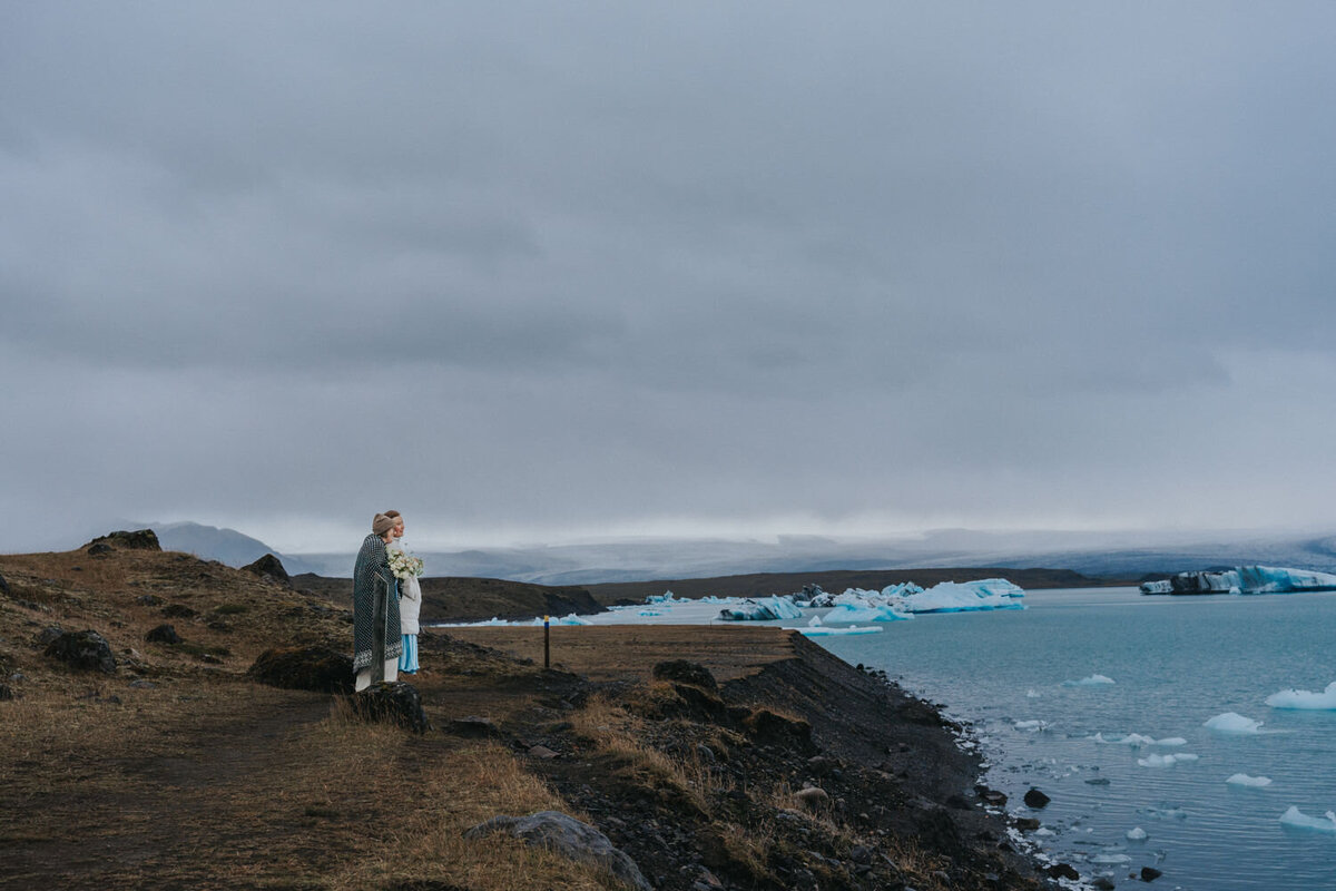 Women stand embracing near the edge of Icelandic cliff 