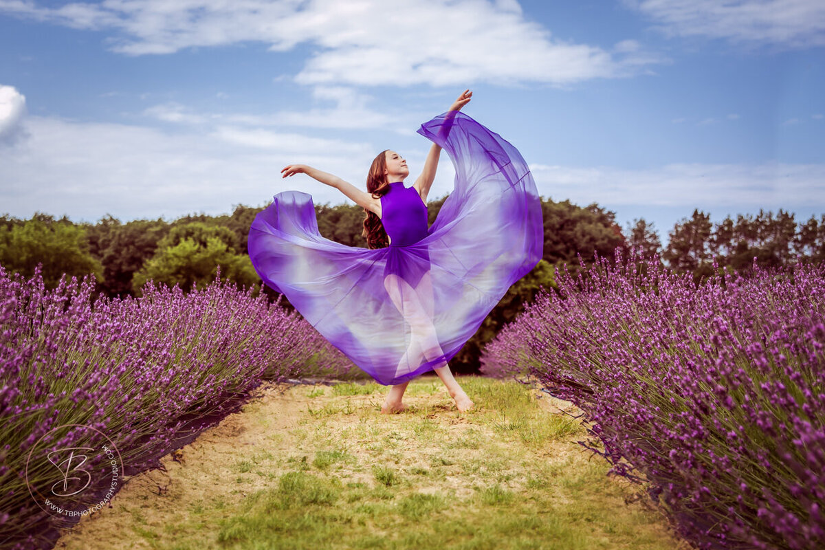 Young female dancer in a lavender field wearing a purple and white ombre styled chiffon dress. 