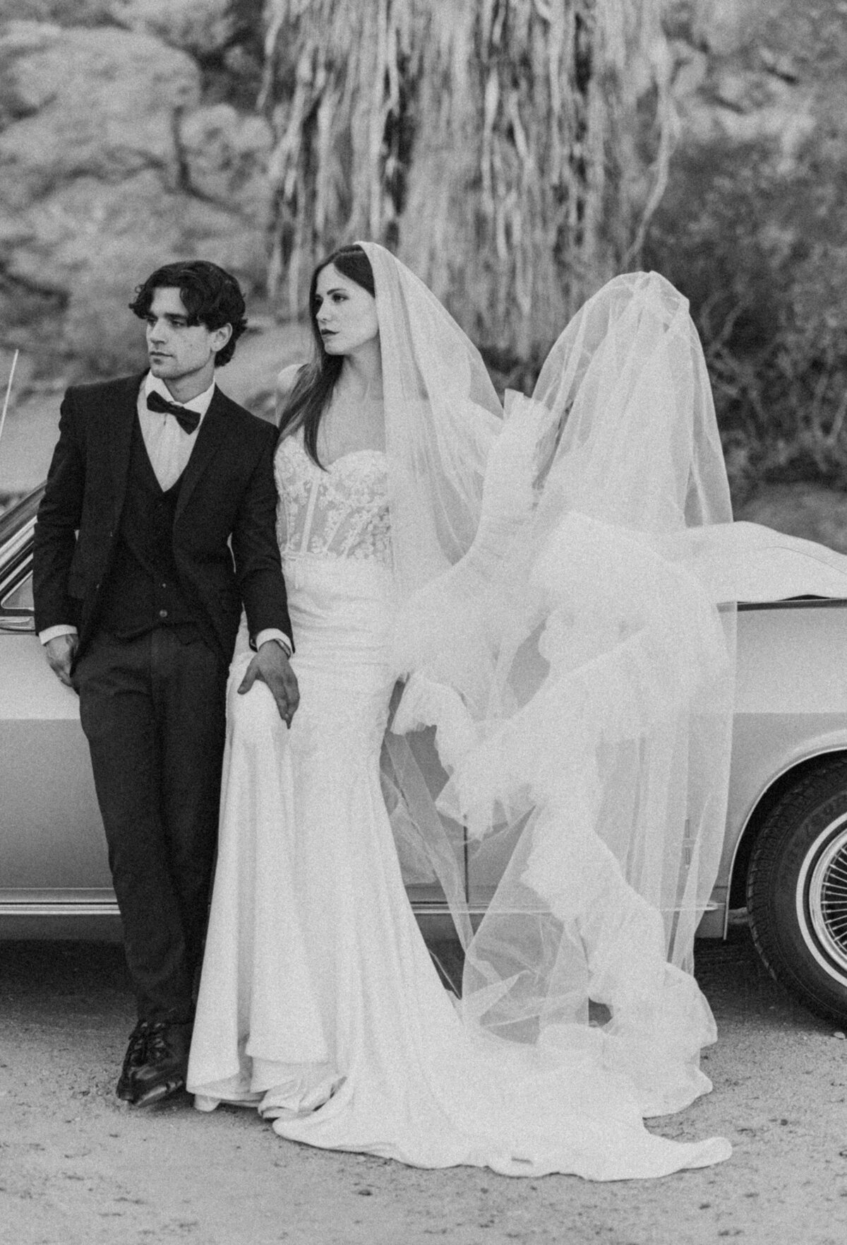 Black and white image of couple during their wedding ceremony, surrounded by guests with a mountain backdrop in Palm Springs.