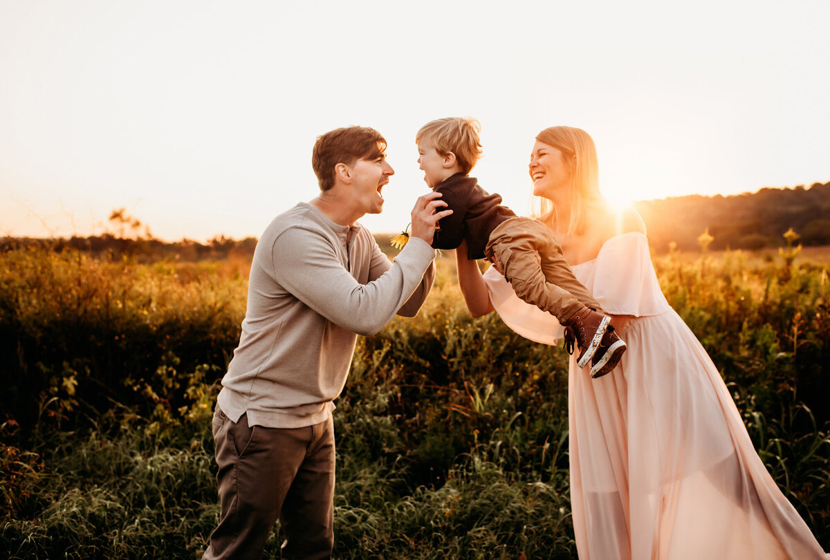 Family Photographer, Mom and Dad playing in the field with their son.