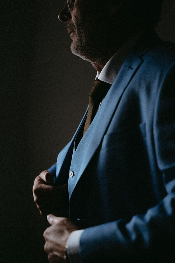 Patrick ajuste son costume bleu. Photo capturée par Kamescop, vidéaste et photographe de mariage.