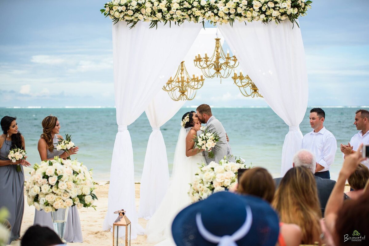 Bride and groom kissing each other on their beach wedding ceremony