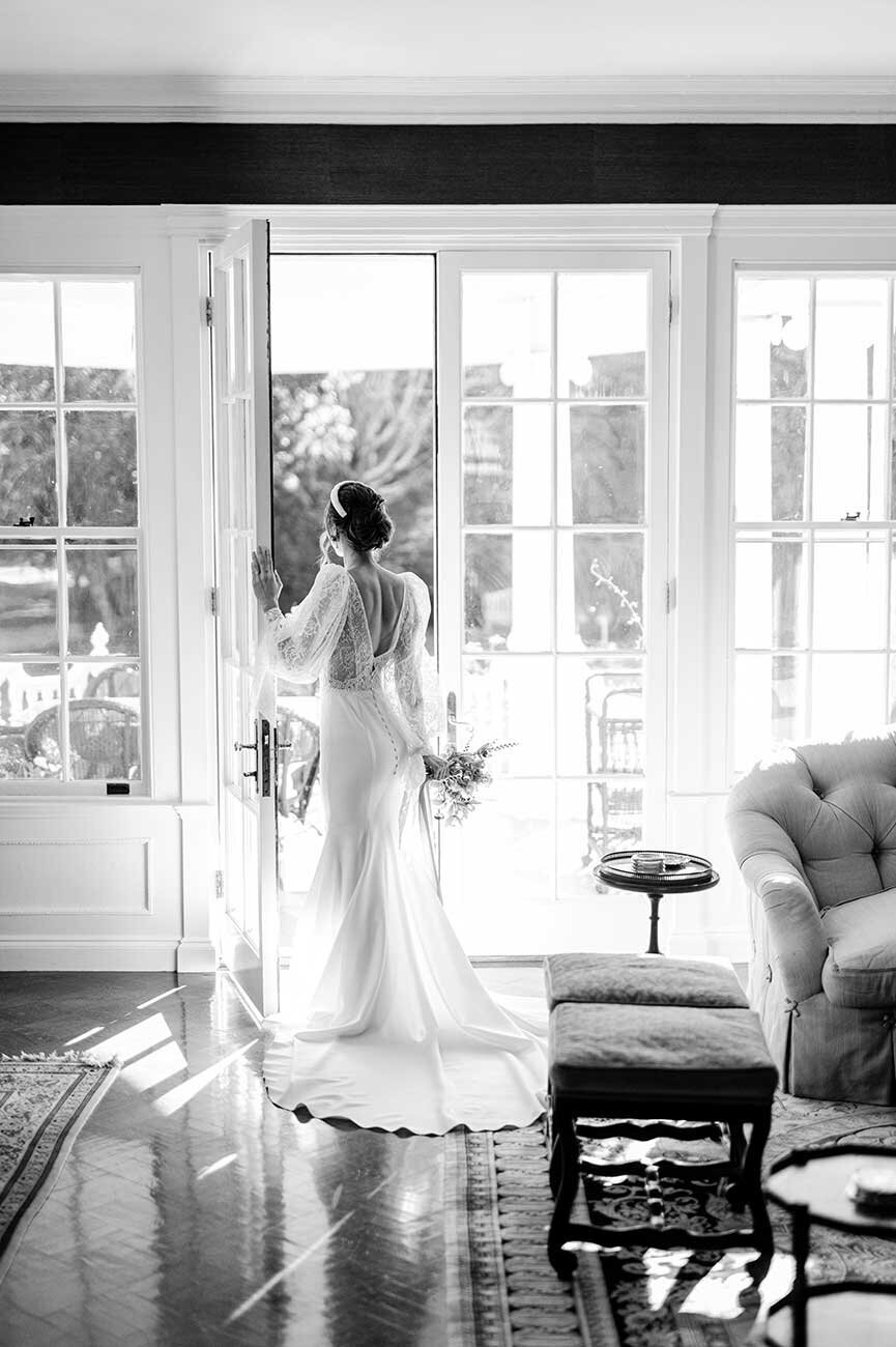 black and white photo of bride looking out window