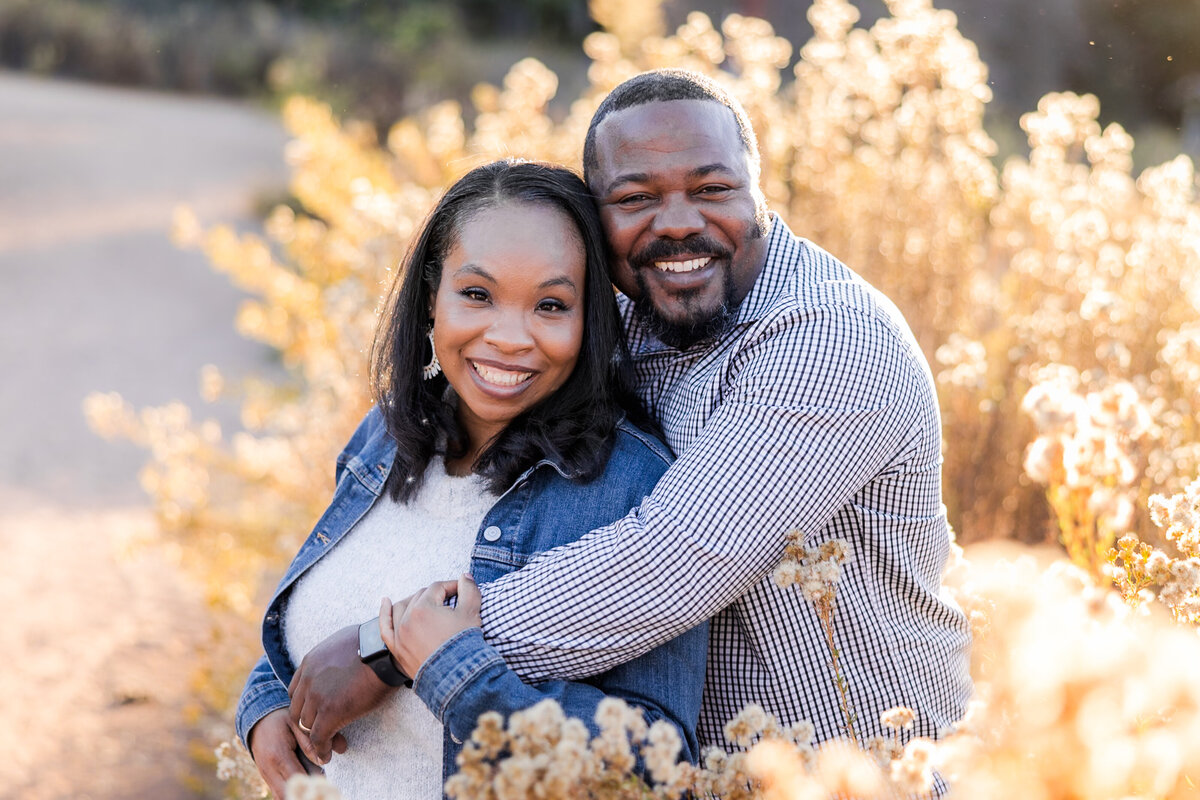 man hugging wife in glowy grass