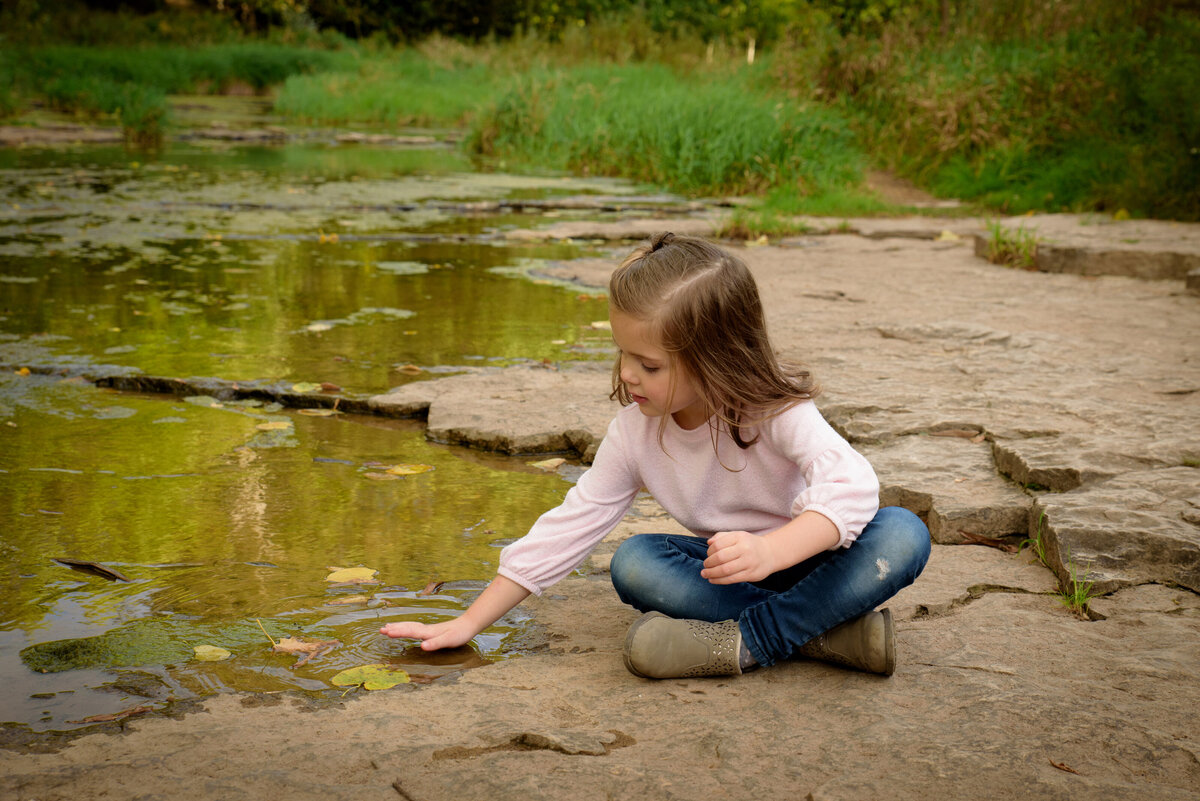 Child portrait of a little girl playing in the water along the banks of a creek at Fonferek Glen County Park near Green Bay, Wisconsin.