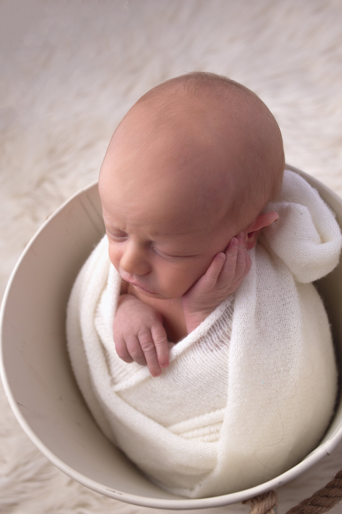 Newborn baby boy wrapped with hand on face during newborn photoshoot with mt Juliet newborn photographer 
