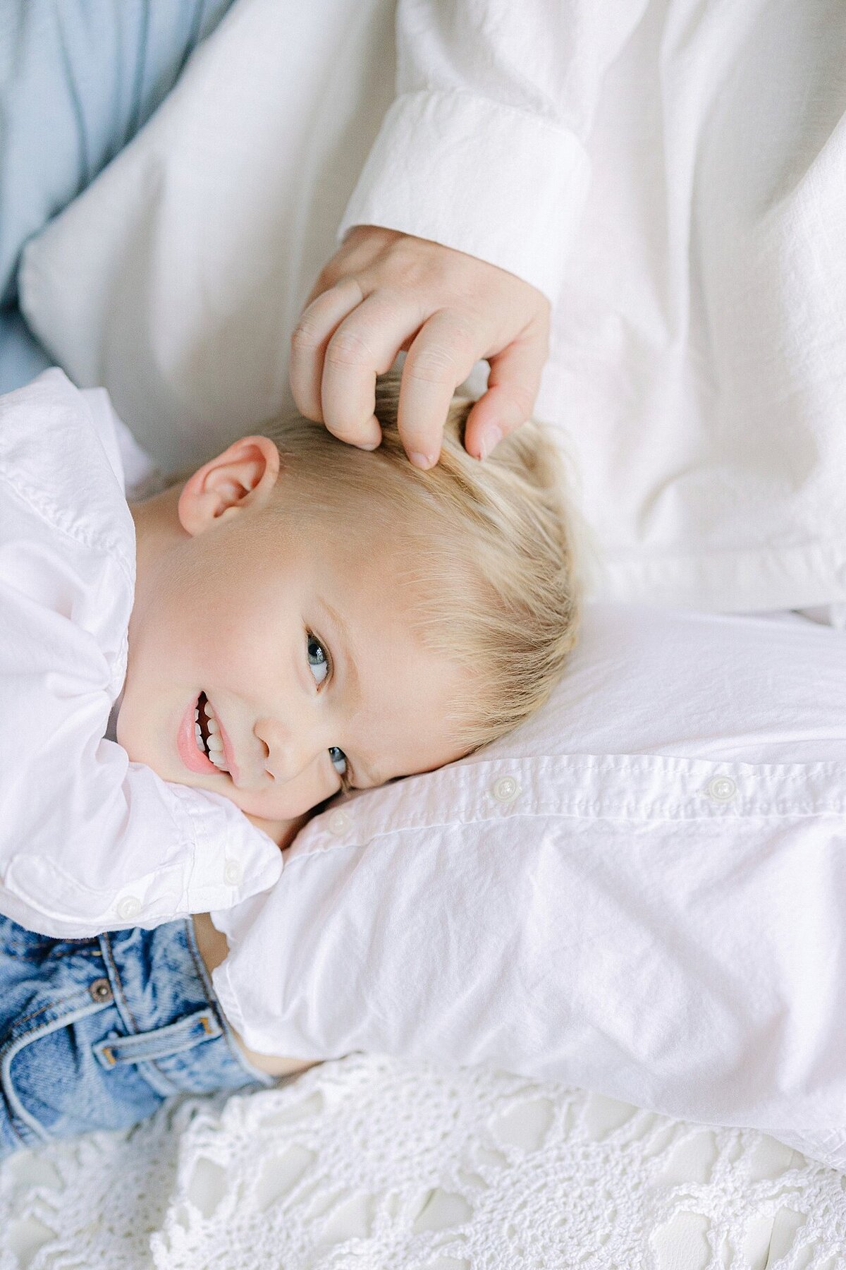 3 year old boy snuggles with his mom and older brother as mom runs her hand through his hair during Indianapolis family photos