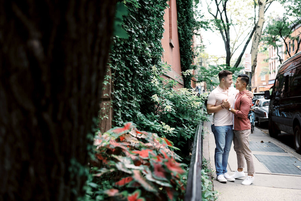 The engaged couple is hugging each other sideways while holding hands at West Village, NYC. Image by Jenny Fu Studio.