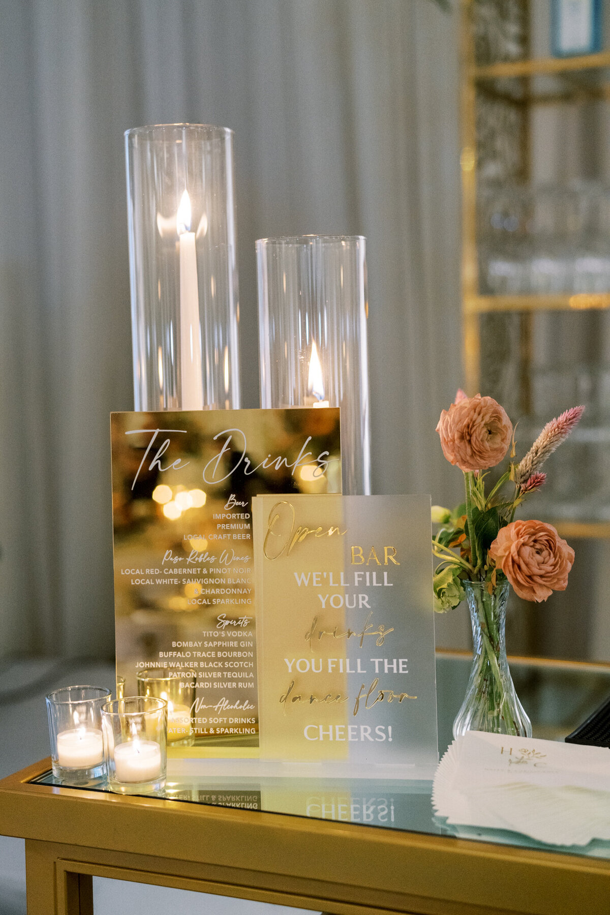 Modern bar signage with gold accents, candlelight, and florals—elevated wedding details with a chic, romantic twist.