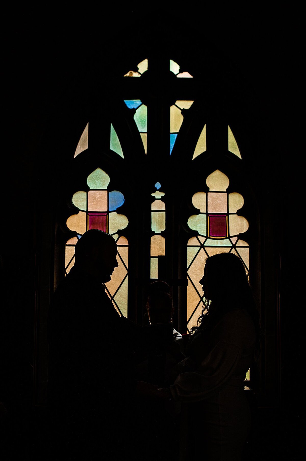 Bride and groom are silhouetted in the stained glass windows of the Skinner Chapel at Scarritt Bennett at their micro wedding.
