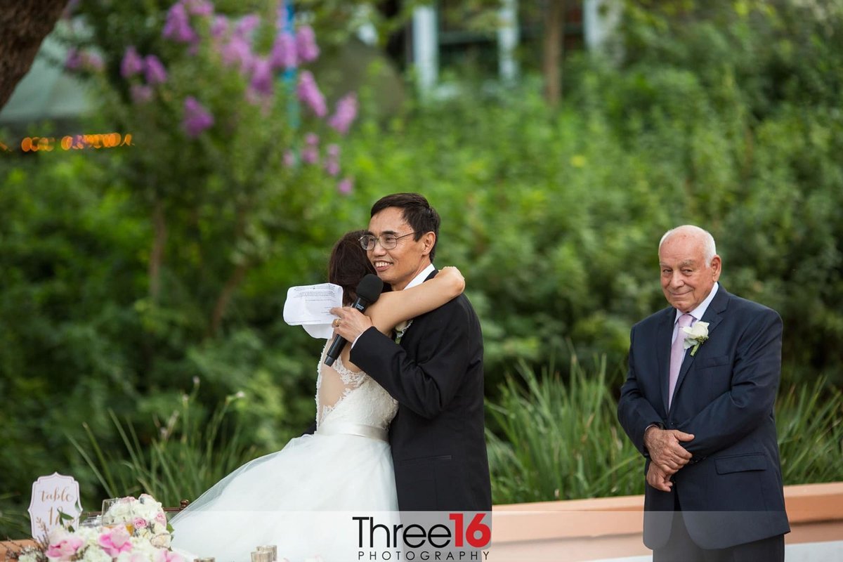 Bride hugs Groom during his reading of his vows