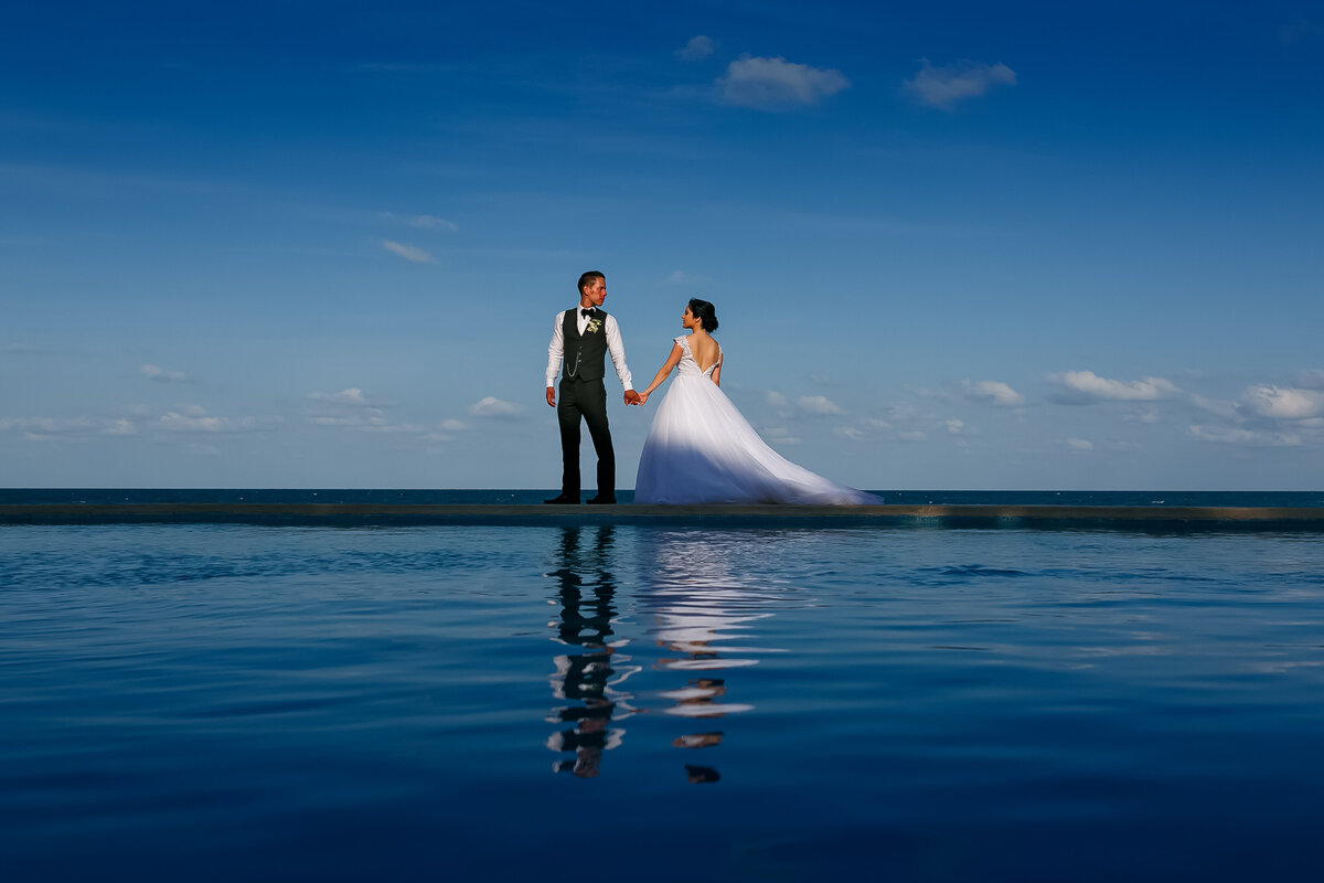 A bride and her groom walk atop of an infinity pool during sunset in Cancun Yucatan Mexico, photo by Tanya Parada