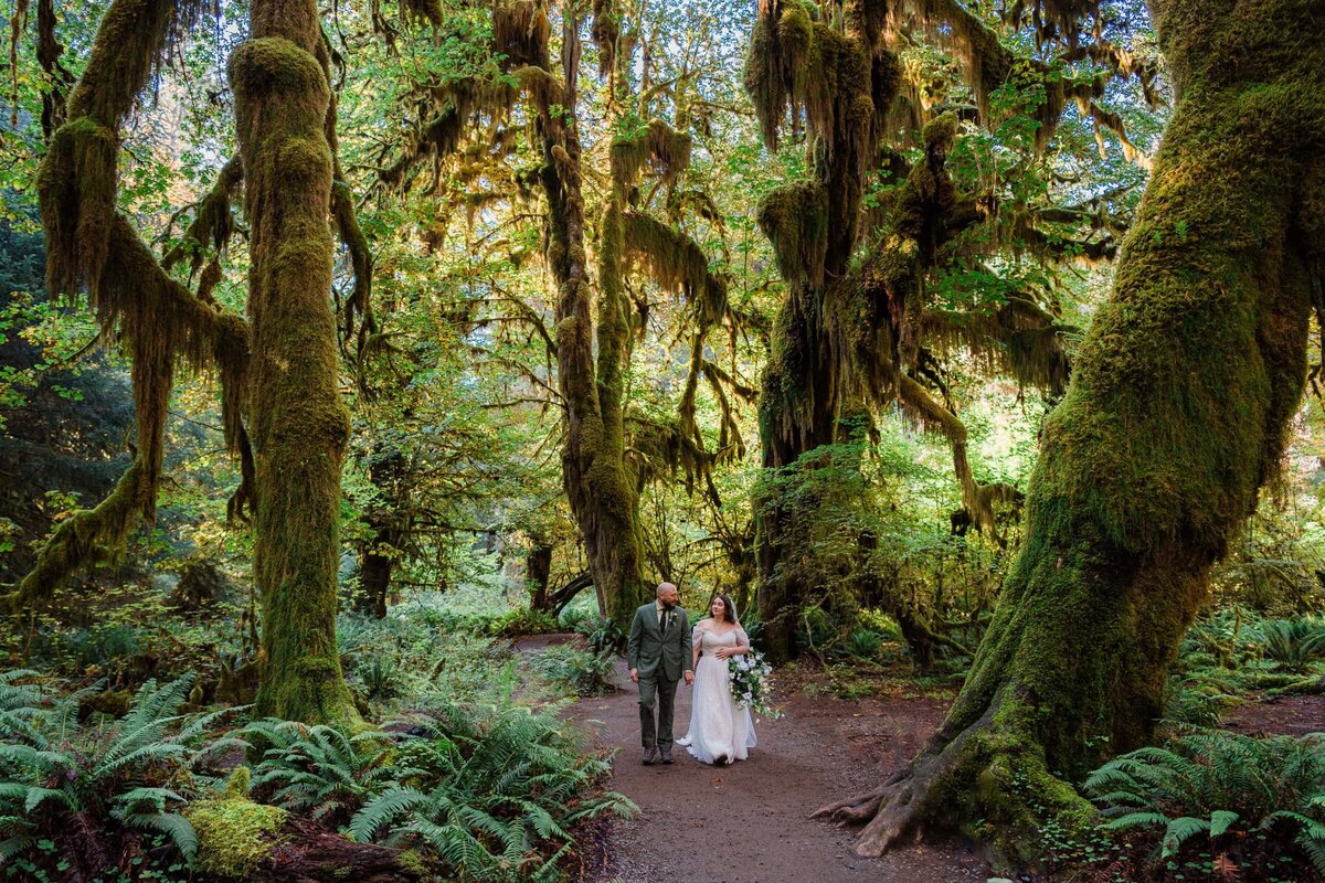 Couple hiking through the Hall of Mossing during their Hoh Rainforest Elopement.
