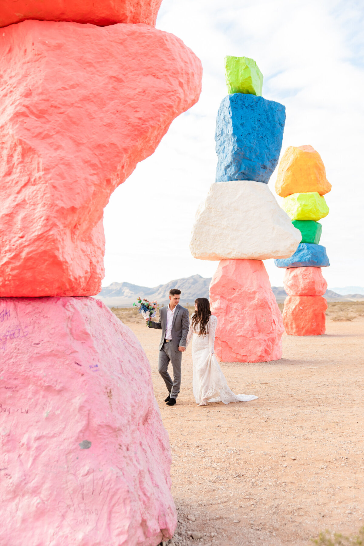 Bride and groom walk past colorful rocks