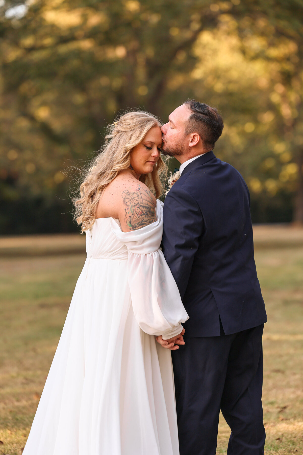 groom kissing bride's forehead and holding hands at Cypress Pond Farm in Doerun Georgia by Georgia wedding photographer Amanda Richardson Photographer