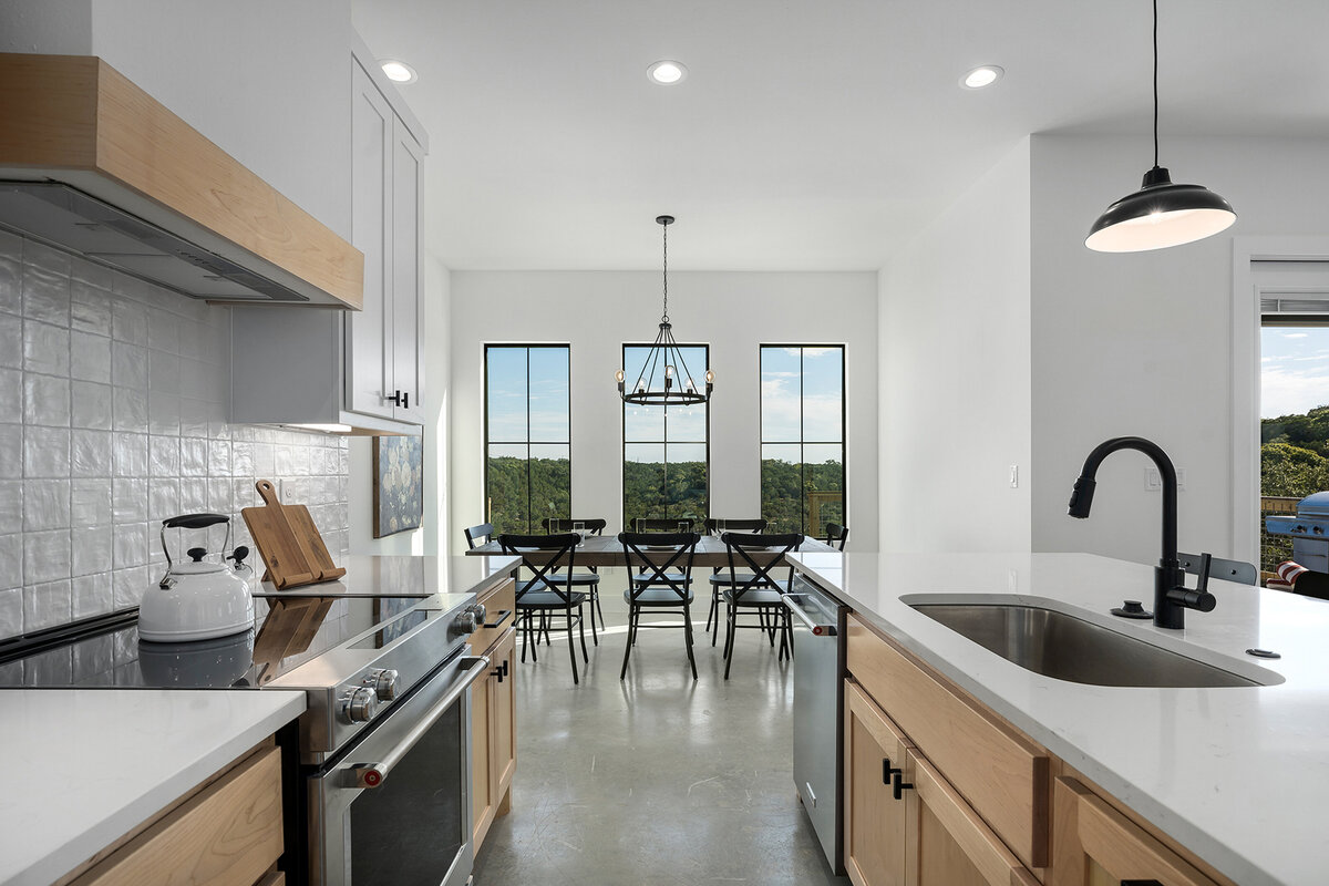 open kitchen with island, white countertops, white backsplash and wood cabinets next to dining room