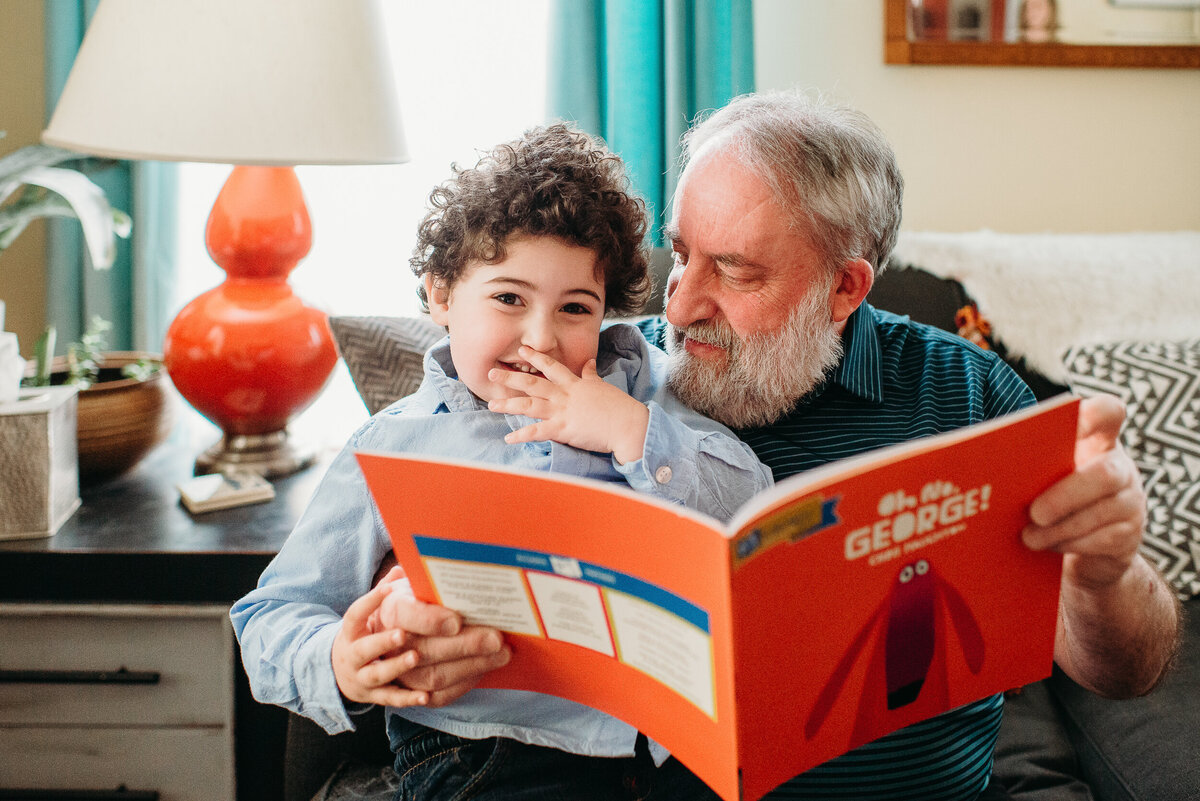 boy laugh while reading a book with grandpa