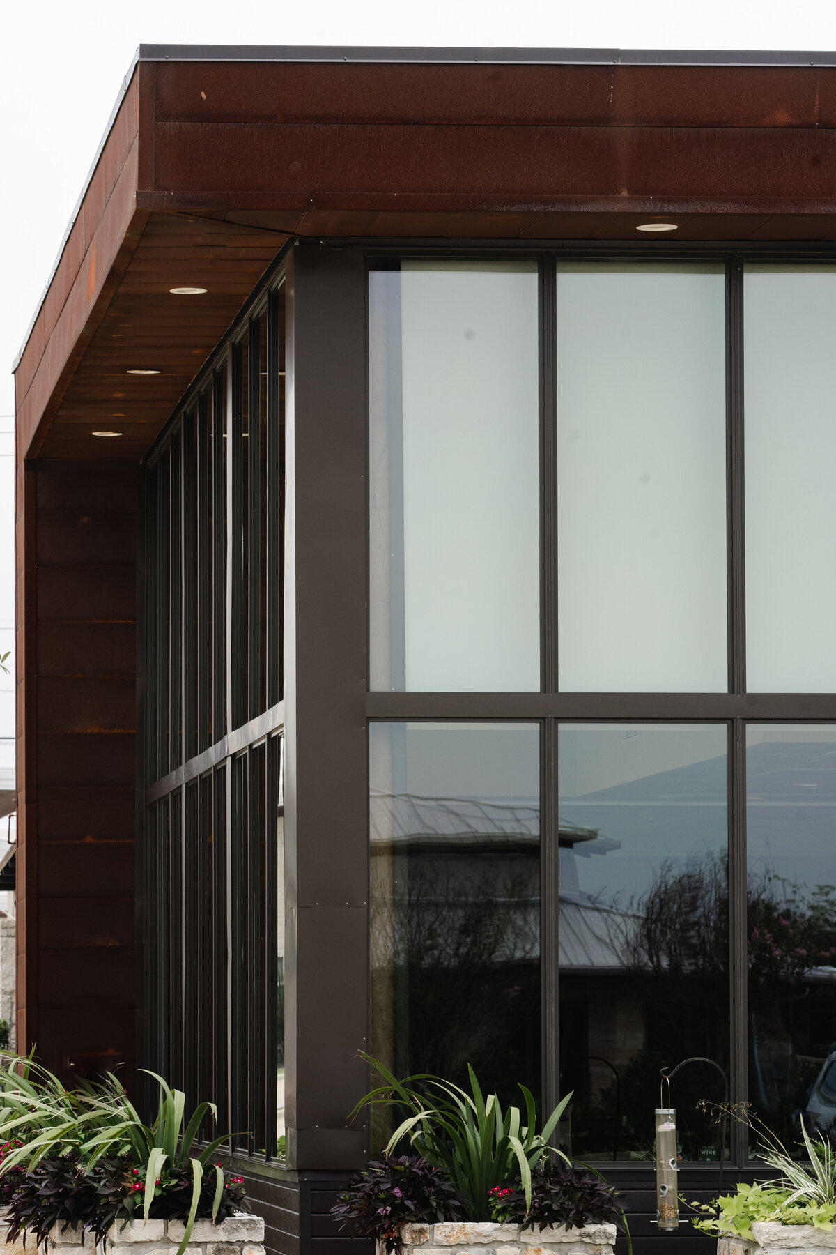 curtainwall glass with black mullions, corten steel roof and planter boxes
