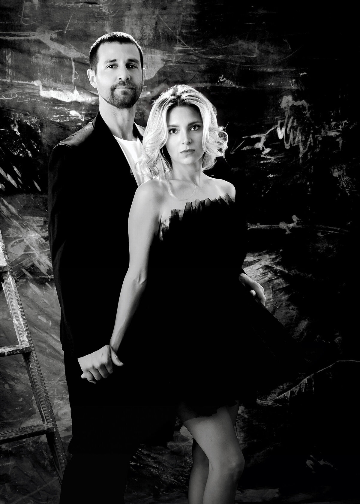 A couple in black & white hold hands and stand together