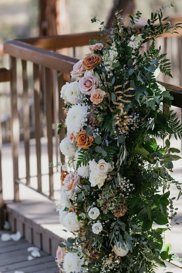 Wedding ceremony flowers with ferns, roses and more.
