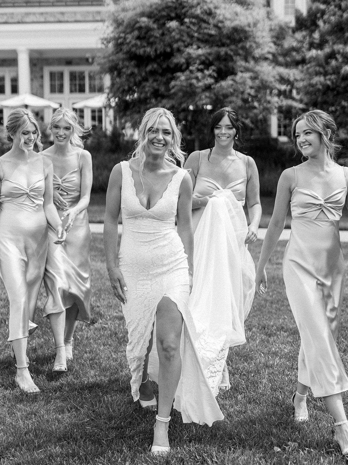 Bride and bridesmaids walk together with joy in this black and white image