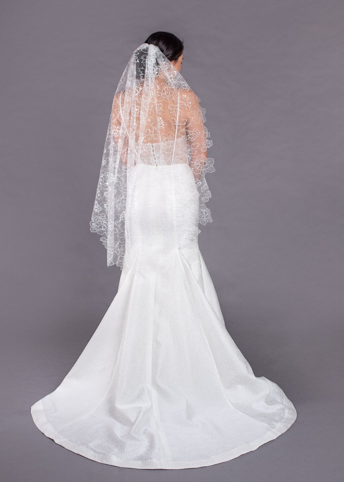 The Lilies Veil is a fingertip-length bridal veil in a sequin and flower embroidered tulle.