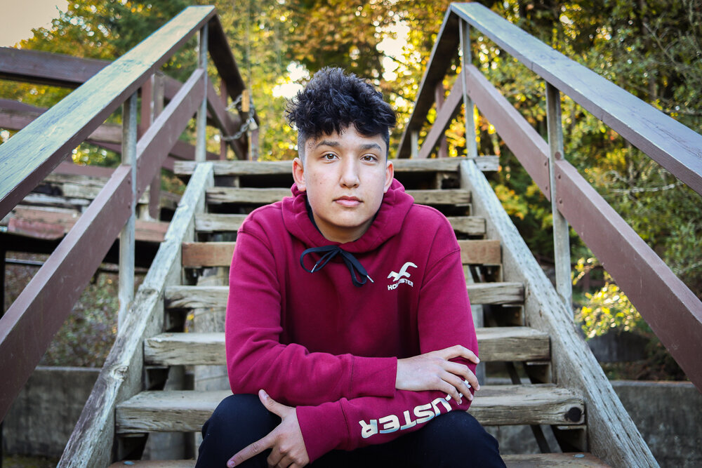 Senior boy posing for his senior pictures on a wooden staircase