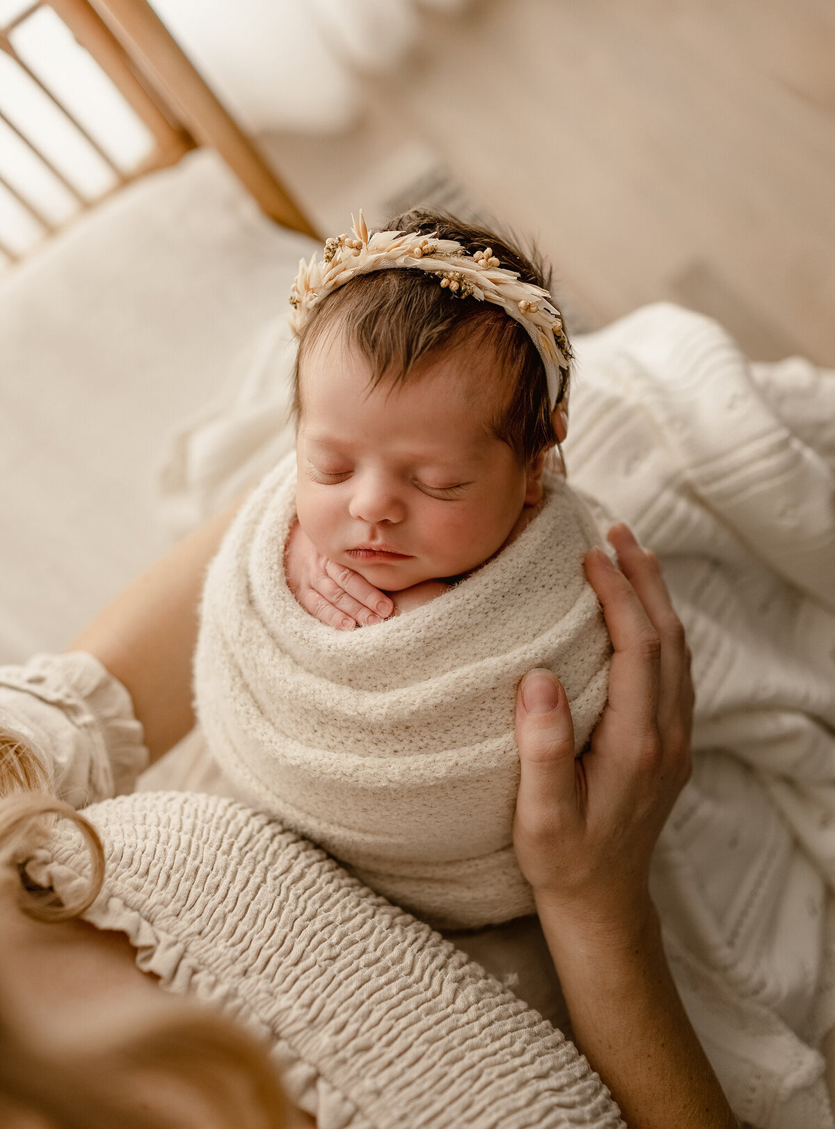 baby cuddled up in mom's arms  during her newborn photos