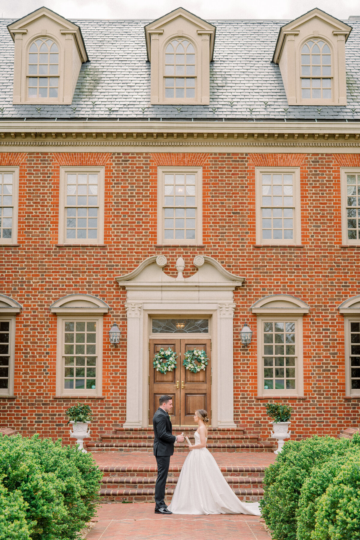 Bride and groom reading their vows to each other in front of the estate at river run