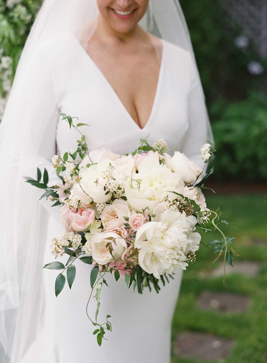 lush garden-style bouquet of white peonies, blush roses, and clematis greenery