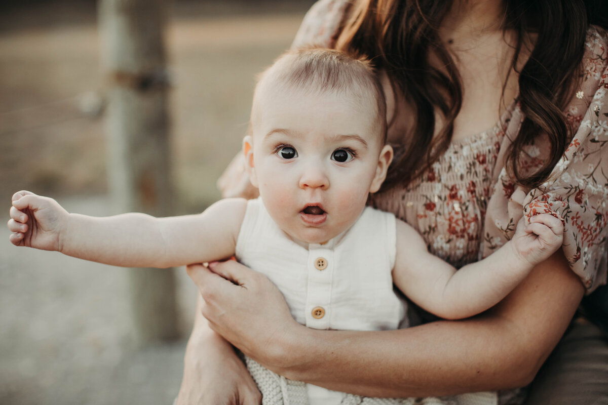 Mom holding her 6-month-old baby boy close, bathed in golden hour light.