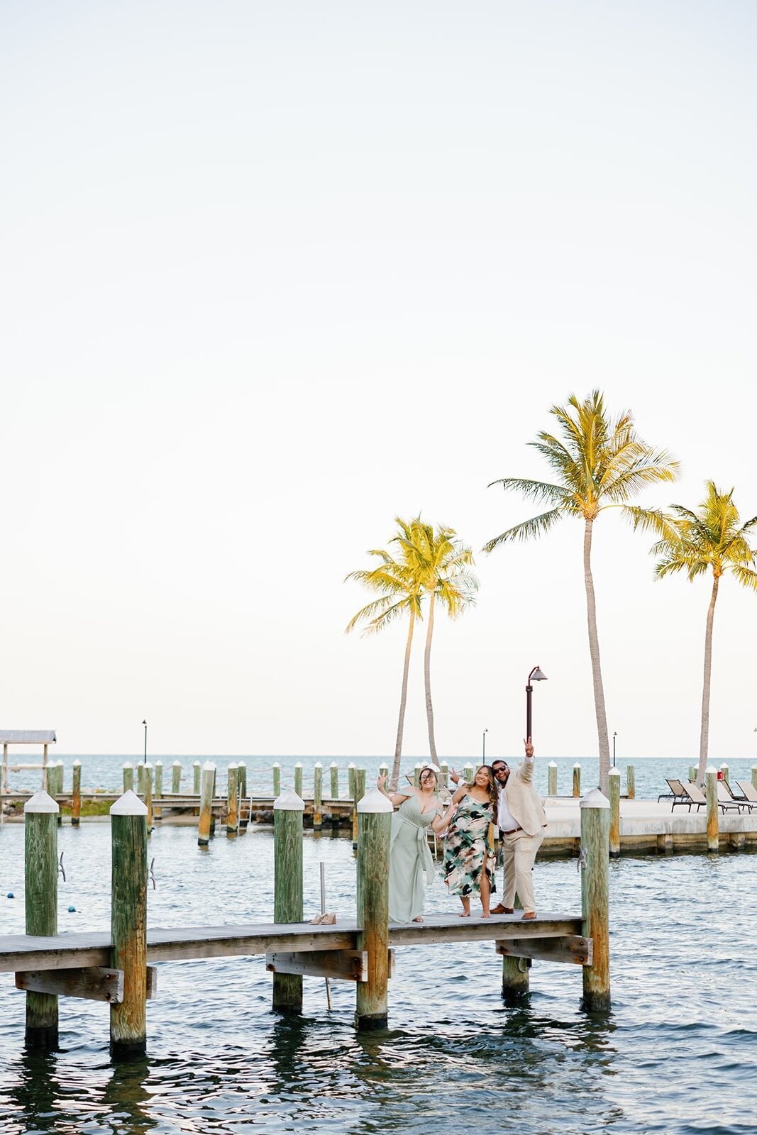 Guests celebrate with playful poses on the wooden pier at this stunning Islamorada destination wedding.